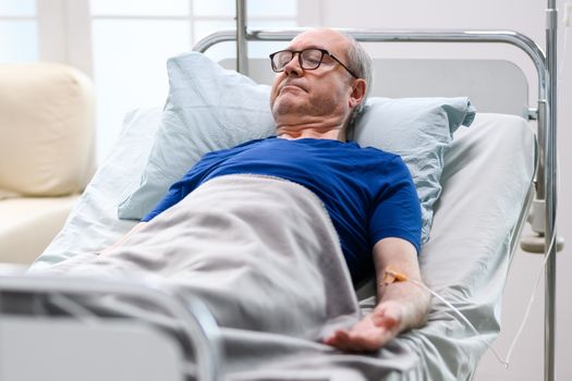 Peaceful retired old man in a nursing home laying in bed.