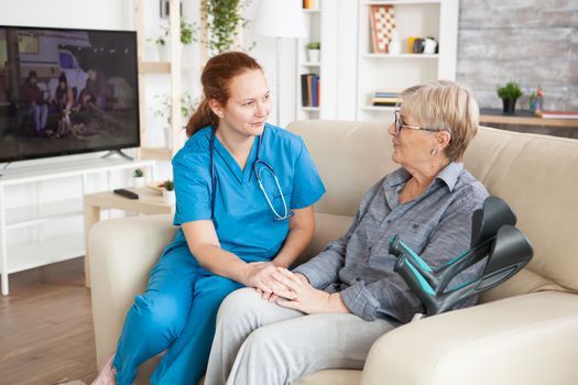 Old woman sitting on a couch in a nursing home telling a story to her assistance.