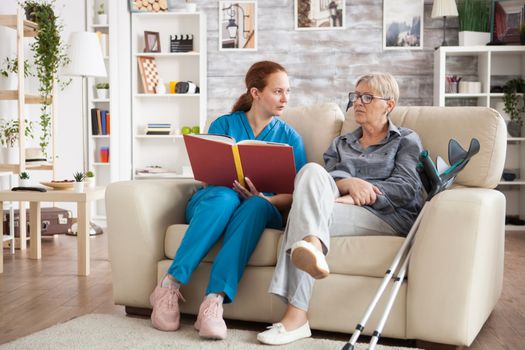 Female nursing reading a book for a senior woman with alzheimer's in a nursing home.