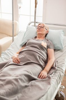 Tired old woman laying on bed in a nursing home. Retired woman.