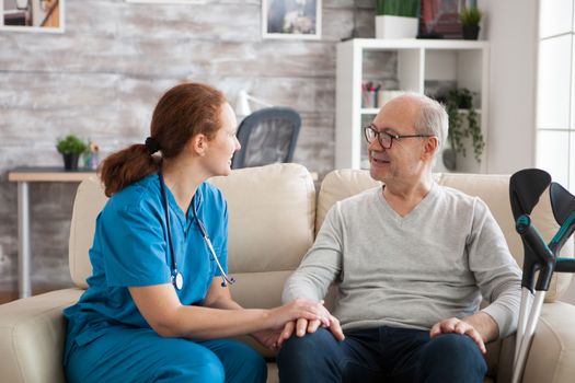 Female doctor with stethoscope in nursing home talking with old patient.