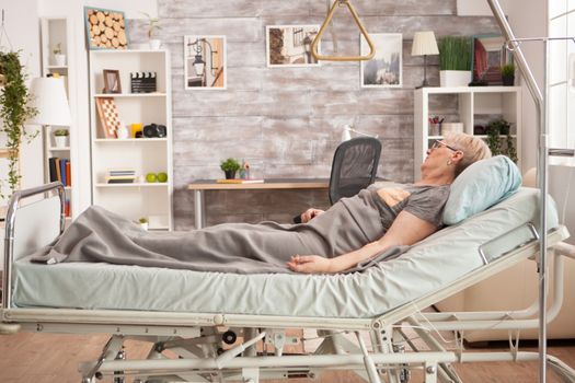 Picture old woman resting in bed in a nursing room. Peaceful pensioner.