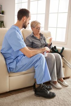 Senior woman in nursing home taking her medicine .Male doctor.