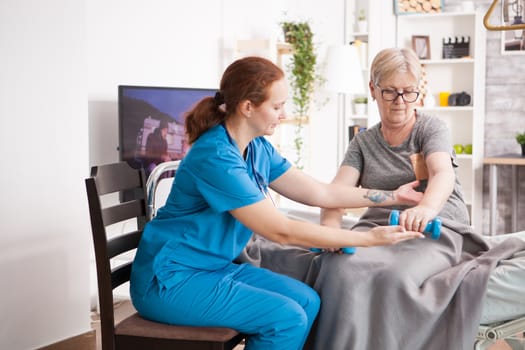 Female doctor and retired woman in nursing home doing exercises.