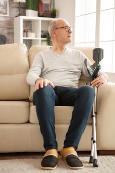 Senior woman in nursing home sitting alone on couch.