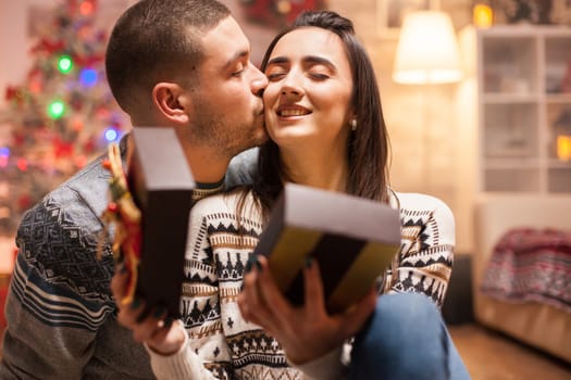 Happy couple kissing her girlfriend cheek after giving her christmas gift.