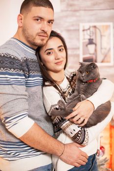 Portrait of happy couple and their cat on christmas day.