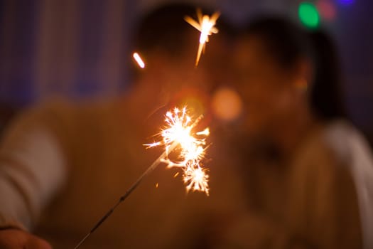 Cheerful young man and his wife holding bengal lights on christmas day.