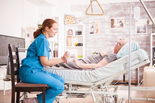 Female doctor showing old woman her pills in nursing home.