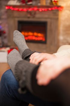 Boyfriend holding his hands on his girlfriend feet celebrating christmas in living room.