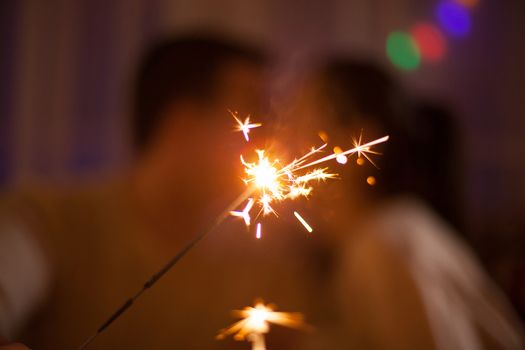 Adorable caucasian couple holding bengal lights on christmas day.