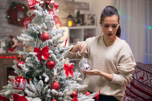 Beautiful young woman holding a crystal globe for her christmas tree.