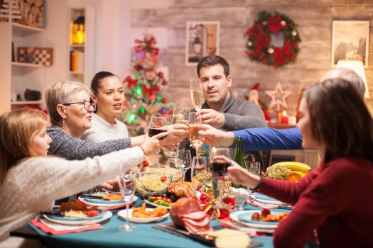 Cheerful big family clinking a glass of wine at christmas celebration.