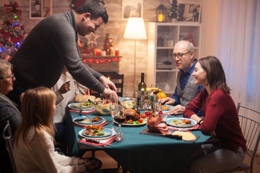 Father slicing the roasted chicken at christmas family celebration