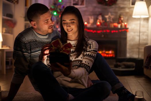 Boyfriend looking how happy his girlfriend is with magical christmas gift.