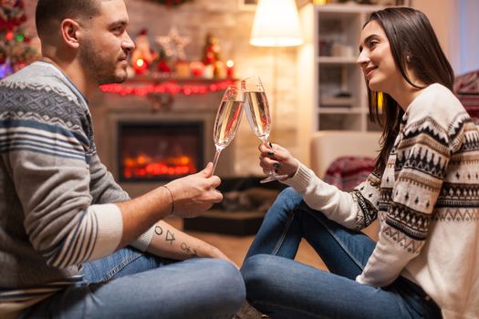 Happy girl thinking how much she loves her boyfriend on christmas day clinking a glass of champagne.