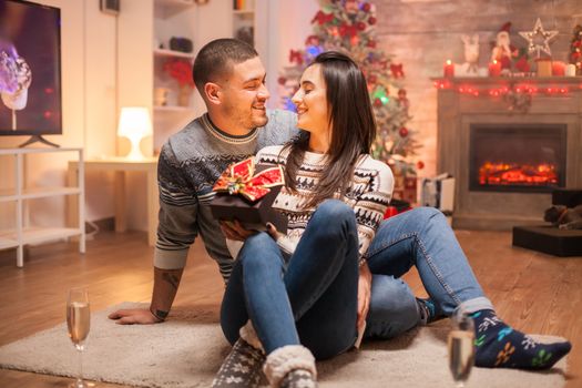 Loving couple with magic gift box celebrating christmas. Warm fireplace.