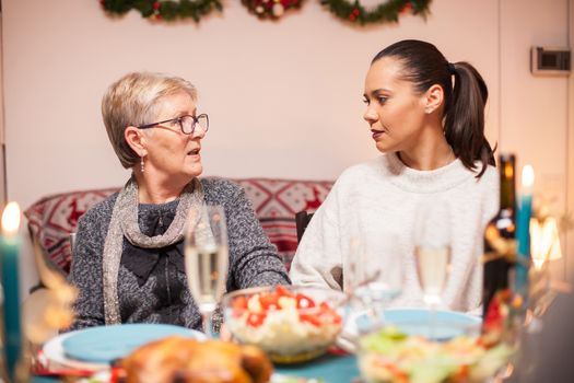Portrait of young woman having a conversation with her mother at christmas family dinner.