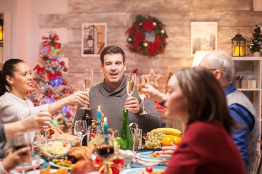 Big family at christmas family dinner toasting with white wine. Delicious food.