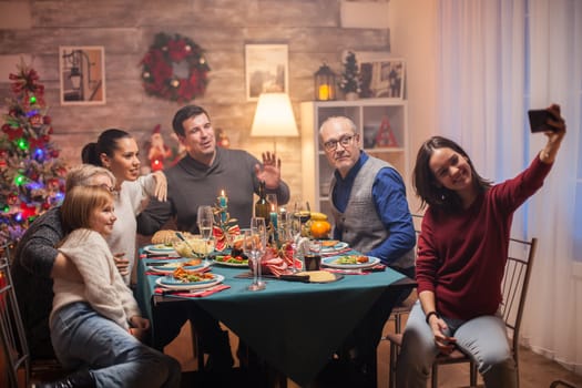 Cheerful granddaughter taking a selfie with her family at christmas celebration.