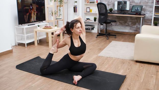 Young woman working on her posture at home doing yoga exercise.