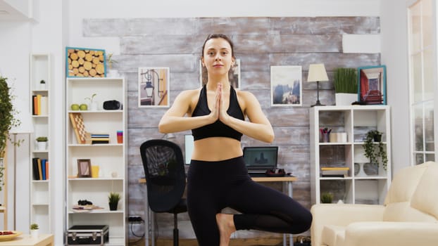 Young woman practice wellness doing yoga pose in living room.