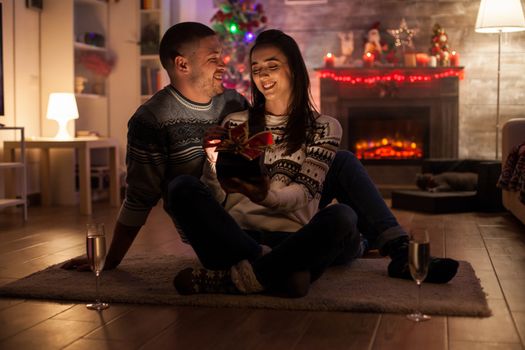 Smiling couple in dark living room happy about magic christmas gift. Cheerful girlfriend.