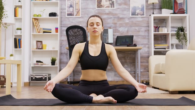 Beautiful young woman in sportswear practicing yoga meditation in lotus postion.