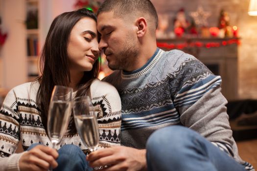 Loving couple keeping their eyes closed on christmas day while holding glasses of champagne.