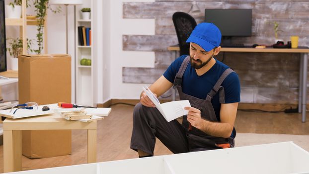 Confused furniture assembly worker while reading instructions to mount a shelf.