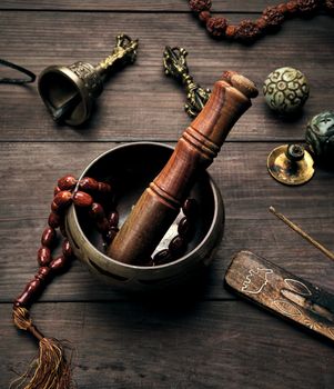 copper singing bowl and a wooden stick on a brown table,  top view
