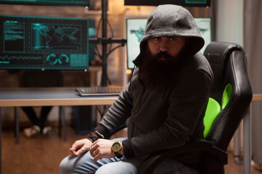 Dangerous bearded hacker wearing a hoodie and looking into the camera.