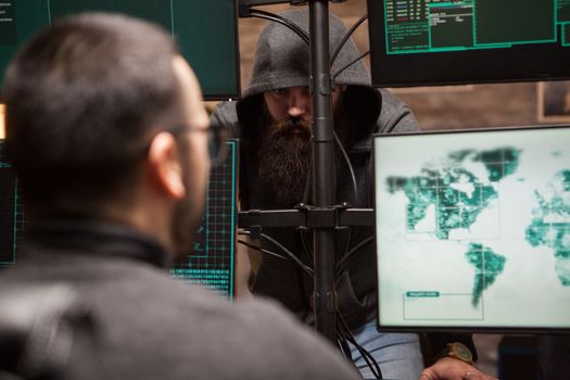 Team of international and dangerous hackers stealing technology. Bearded hacker with hoodie.