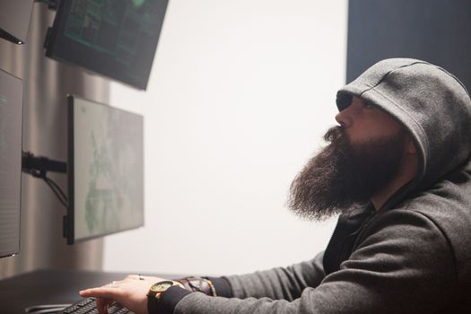 Focused bearded hacker to destroy the system making a dangerous malware.