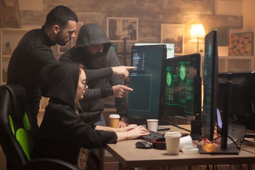Team of hackers pointing on computer screen and female cyber terrorist.