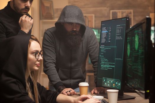 Bearded hacker wearing a hoodie while his team breaks vulnerable government servers.