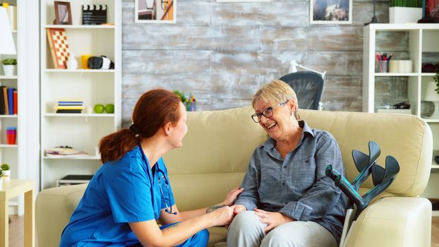 Female nurse talking with old woman with alzheimer in nursing home