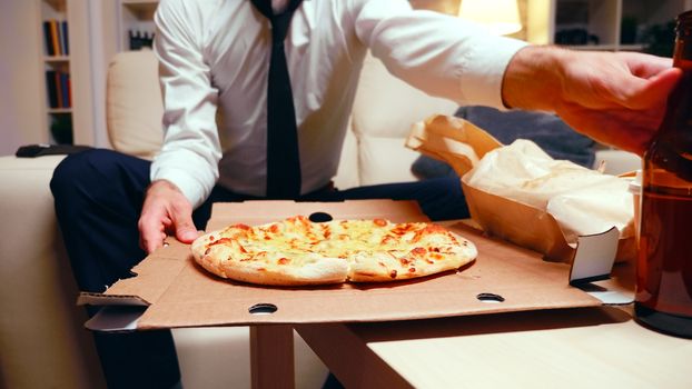 Businessman arriving home with pizza after a long day at work. Resting after work.