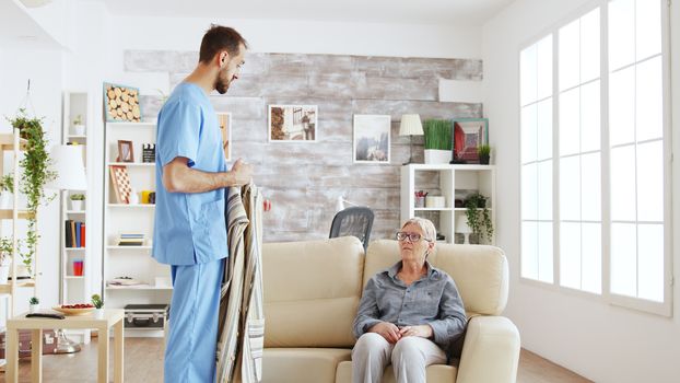 Male nurse helping senior woman getting dressed in nursing home