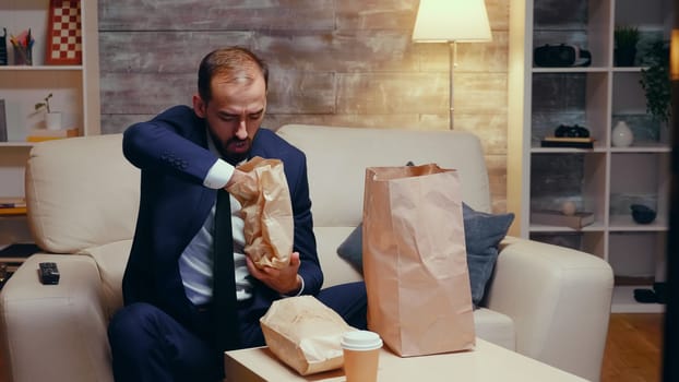 Follow shot of hungry caucasian businessman in suit with takeaway food.
