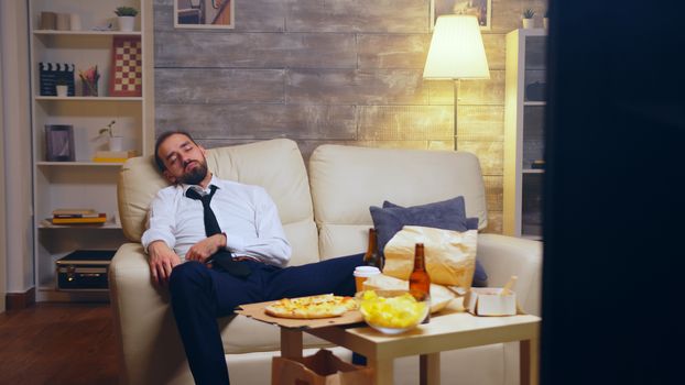 Young businessman in suit falling asleep on the couch still dressed in suit