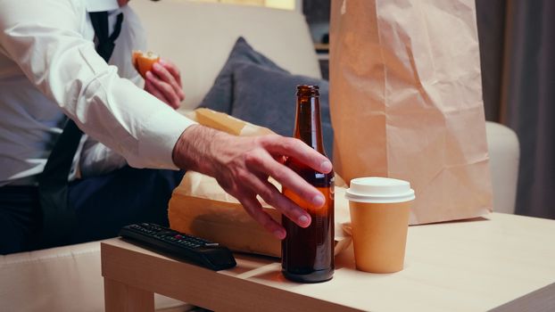 Businessman in his home resting and drinking beer. Unhealthy food