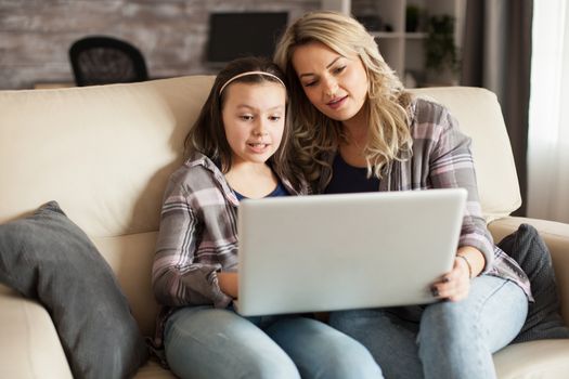 Young mother using modern technology for his daughter education using a laptop with wireless connection.