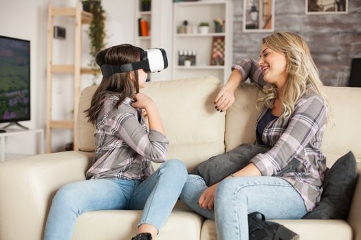 Happy little girl with virtual reality glasses playing games. Beautiful mother.