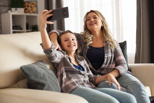 Caucasian mother and daughter having a good relationship. Parent and kid taking a selfie.