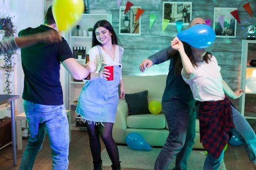 Attractive young woman smiling while dancing with her friend at a party.