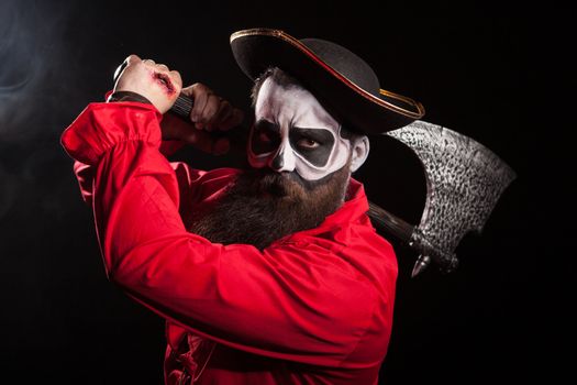 Man dressed up like a pirate for halloween holding and axe over black background.