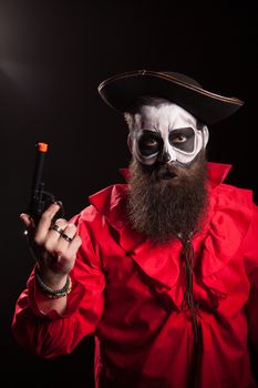 Crazy and spooky medieval pirate with his pistol over black background. Halloween outfit.
