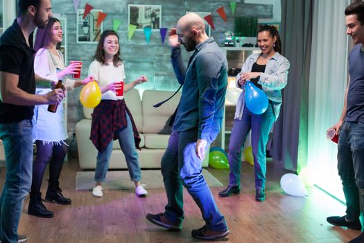 Handsome man showing his robot dance moves while partying with group of people.