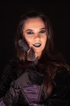 Witch with an evil face over black background . Halloween costume.